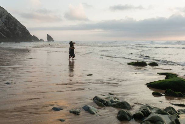 vista posteriore di uomo e donna che si abbracciano in piedi nell'acqua dell'oceano  - Foto, immagini
