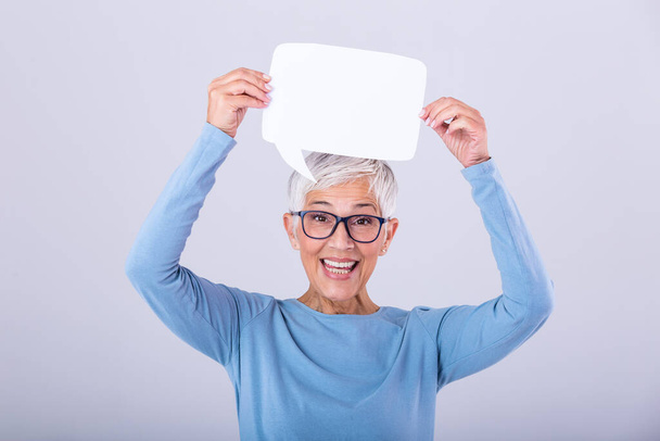 Cheerful mature woman holding speech bubble sign over her head and smiling. Happy senior lady with speech bubble banner Woman showing sign speech bubble banner looking happy - Foto, immagini