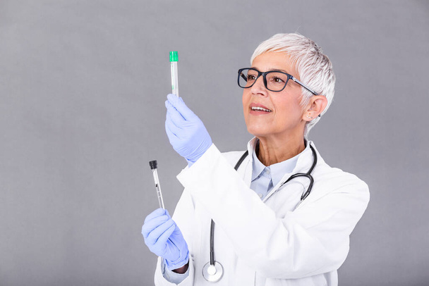 Жінка-лікар або технік тримає пробірку Медичне обладнання. Тест на кров або вірус. Старша лікарка, яка працює з зразками крові в пробірках, крупним планом
 - Фото, зображення