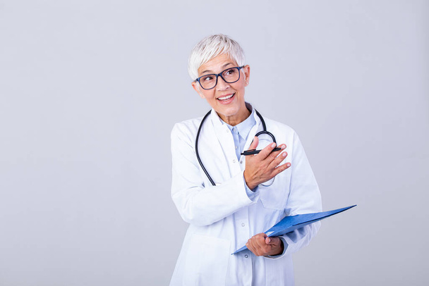 Happy smiling senior female doctor writing on clipboard, isolated on background. Medicine and health care concept. Smiling mature medical doctor woman with stethoscope. - Φωτογραφία, εικόνα