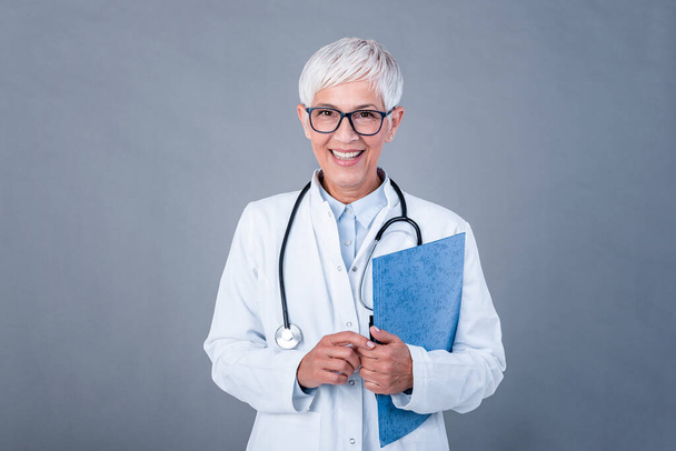 Female mature doctor holding medical records and stethoscope. Healthcare and medical concept. Medicine doctor with stethoscope isolated on background. - Foto, Imagen