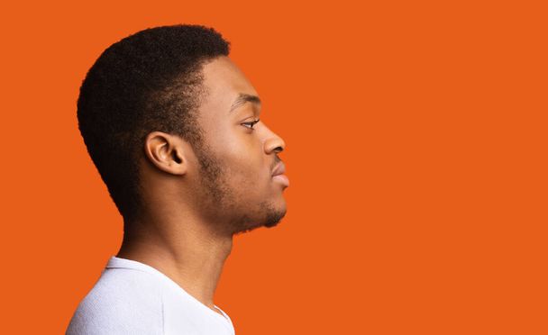 Profile Portrait Of Serious African American Man Looking Aside At Copy Space Posing Over Orange Studio Background. Offer Advertisement Concept. Side View Shot - Foto, Imagem