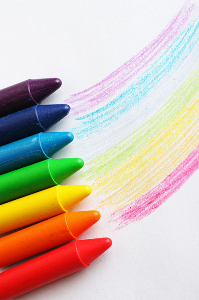 Oil pastel crayons lying on a paper with pictured rainbow - Photo, Image