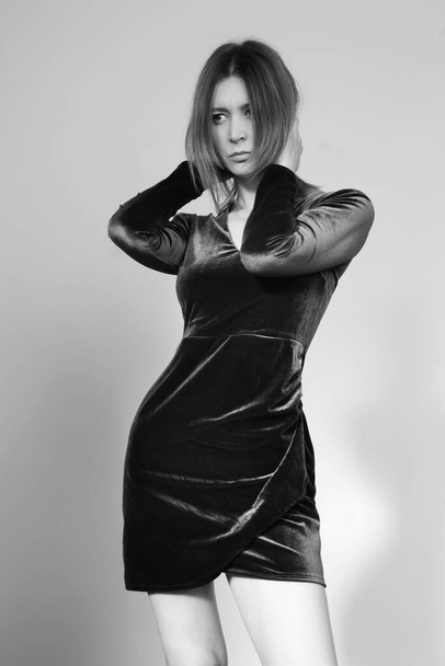 Studio portrait of young female model in black plush dress, autumn winter fashion collection. - Foto, afbeelding