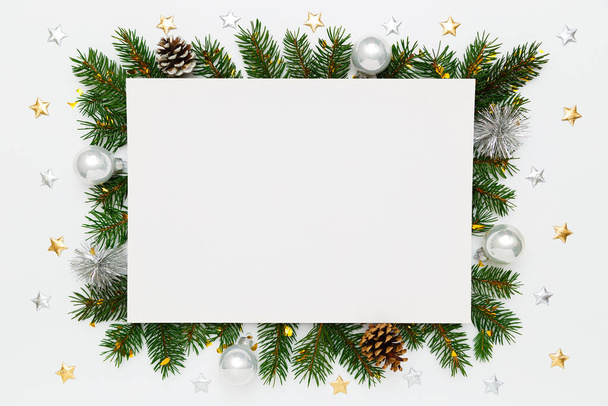 Christmas, New Year holiday layout with copy space for text. Blank white paper, natural fir tree branches and pinecones, decorations, silver balls, stars on white flat lay background - Foto, Imagem