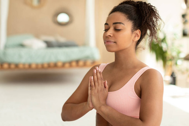Розумна гармонія. Портрет спокійної чорної леді, що медитує закритими очима, практикує медитацію або молитву, тримає руки в жесті імен, вільний простір
 - Фото, зображення