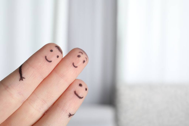 Three fingers with drawings of happy faces on blurred background, space for text - Fotó, kép