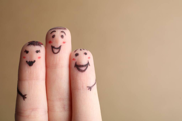 Three fingers with drawings of happy faces on brown background, space for text - Photo, image