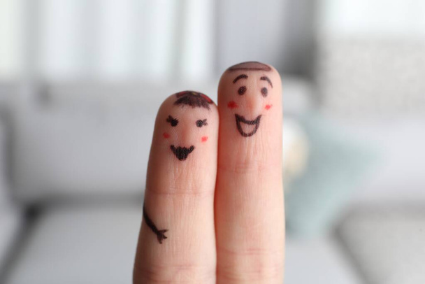 Two fingers with drawings of happy faces on blurred background. Spending time together - Photo, image