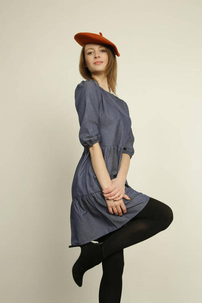 Серія студійних фотографій молодої жіночої моделі в повсякденному блакитному бавовняному джинсовому сукні міді та береті з коралової вовни. осінь зимова мода
. - Фото, зображення