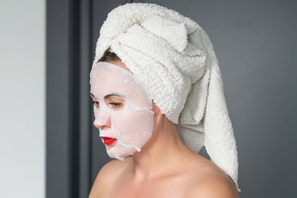 Home facial care, cloth mask on girl's face, girl wrapped in a towel. - Foto, Imagem