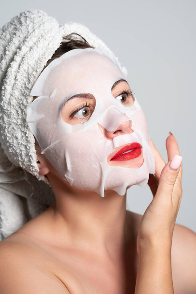 Fabric refreshing face mask, skin care, portrait of a woman with a mask on her face. - Foto, Imagem