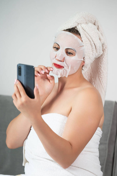 Facial skin cleansing procedure using a cosmetic mask, woman talking on the phone online, women's tricks and beauty. - Foto, Imagem