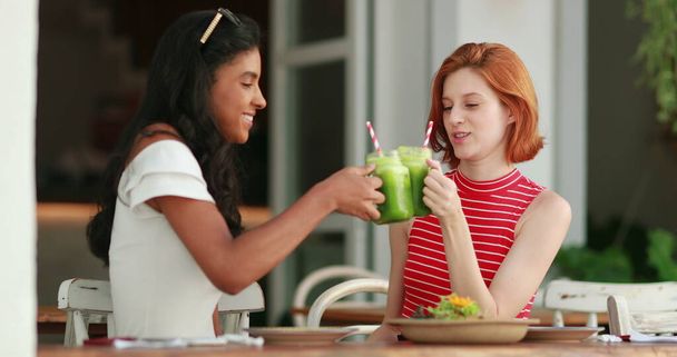 Multiracial friends toasting green juices. Multi-ethnic friendship clinking veggie juice - Фото, изображение