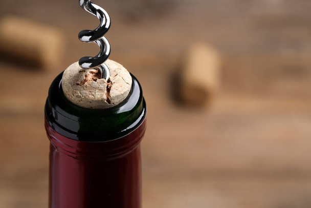 Opening wine bottle with corkscrew on table, closeup. Space for text - 写真・画像