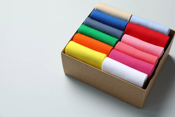 Box with different colorful socks on light background. Space for text - Fotoğraf, Görsel