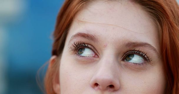 Pensive Woman thinking, eyes looking up. Closeup of redhair girl wondering and reasoning using mental energy - Photo, Image
