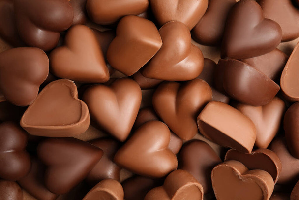 Tasty heart shaped chocolate candies as background, top view. Valentine's day celebration - Foto, Imagen