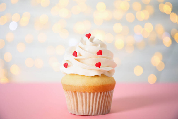 Tasty cupcake for Valentine's Day on pink table against blurred lights - Photo, image