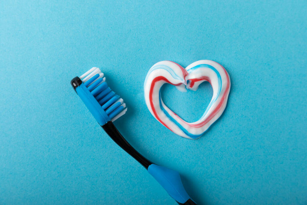 Oral care. Dental care. Composition with a toothbrush and a heart with toothpaste on a blue background. Teeth love concept.Copy space. Place for text.Fletley - Zdjęcie, obraz