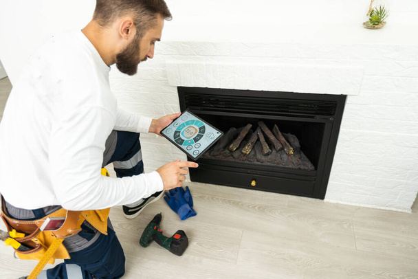 Service technician with tablet repairing a fireplace in a home. - Фото, изображение
