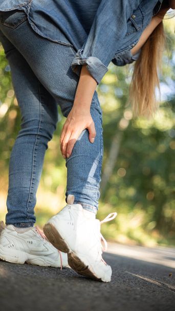 leg pain, cramp after cycling girl in jeans. High quality photo - Φωτογραφία, εικόνα