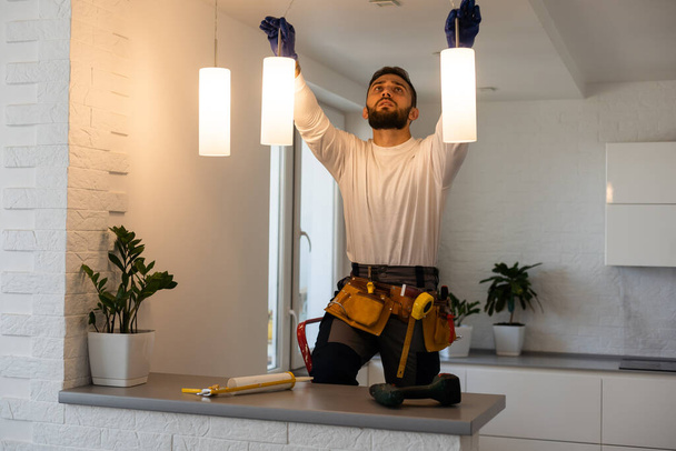 Electricista trabajador instalación lámparas eléctricas luz interior apartamento. Concepto de decoración construcción
 - Foto, Imagen