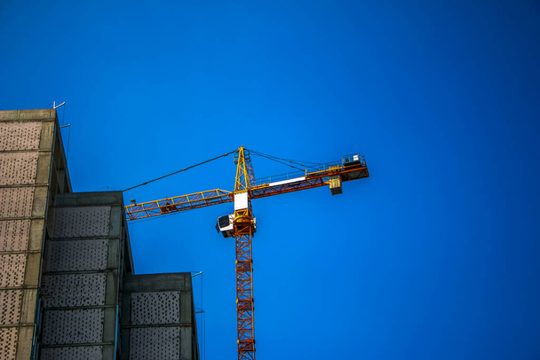 Будівельний кран проти блакитного неба. Індустрія нерухомості. Кран використовує підйомне обладнання на будівельному майданчику
. - Фото, зображення