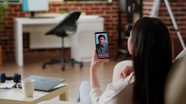 Employee working remotely from home while using talking with coworker on virtual online videoconference call. Young adult woman discussing with work colleague on digital videocall using phone. - Filmagem, Vídeo