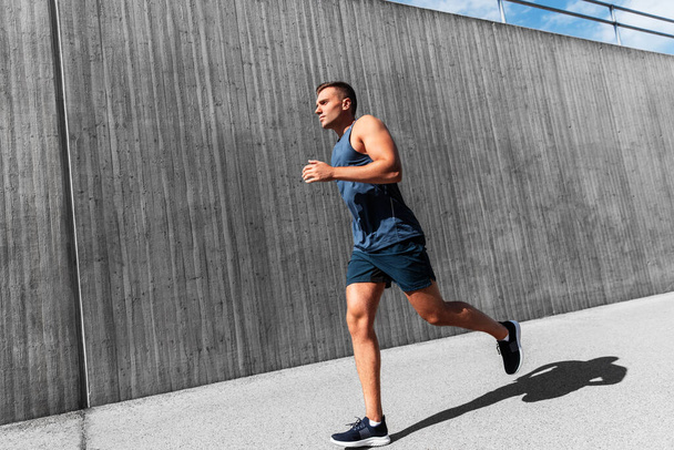 fitness, sport and healthy lifestyle concept - young man running outdoors - Foto, Imagen