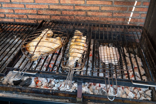 Fresco peixe grelhando em parrilhas de carvão velho peixe branco robalo e pregado, construir fora de edifícios na pequena aldeia de pescadores Getaria, País Basco, Espanha - Foto, Imagem