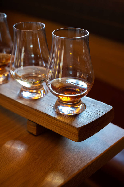 Flight of single malt scotch whisky in glasses served in bar in Edinburgh, UK, tasting of dram of whiskey - Photo, image