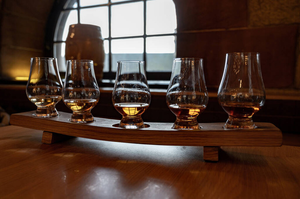 Flight of single malt scotch whisky in glasses served in bar in Edinburgh, UK, tasting of dram of whiskey - Photo, image