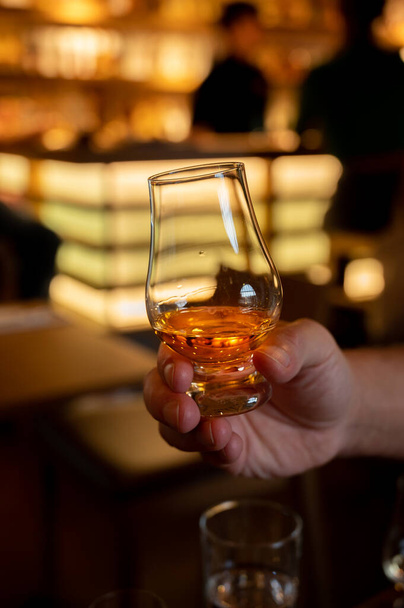 Tasting of single malt scotch whisky in scottish bar in Edinburgh, UK, hand with glass of whisky - Foto, immagini