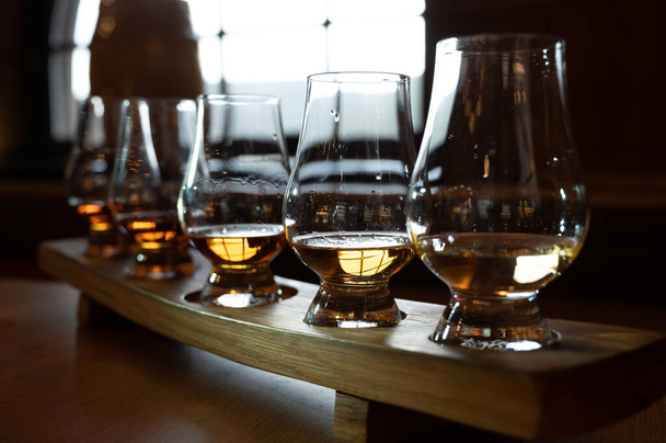 Flight of single malt scotch whisky in glasses served in bar in Edinburgh, UK, tasting of dram of whiskey - Фото, изображение