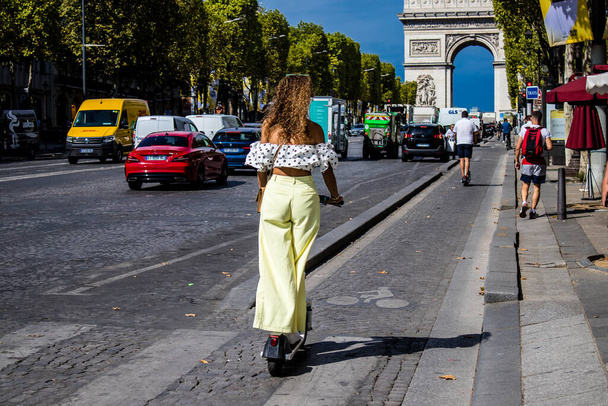 Paris, France - September 05, 2022 People rolling with an electric scooter in the streets of Paris, operating with a small utility internal combustion engines and a deck in the center - 写真・画像
