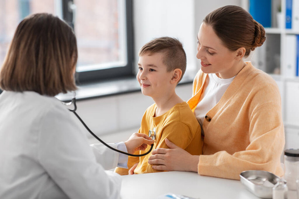 medicine, healthcare and pediatry concept - happy smiling mother with little son and doctor with stethoscope at clinic - Valokuva, kuva