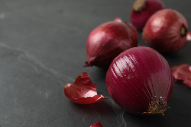 Reife rote Zwiebelzwiebeln auf schwarzem Schiefertisch, Nahaufnahme - Foto, Bild