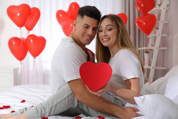 Lovely couple with gift in room. Valentine's day celebration - Φωτογραφία, εικόνα