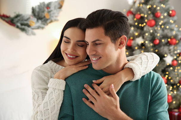 Happy couple near decorated Christmas tree indoors - Фото, зображення