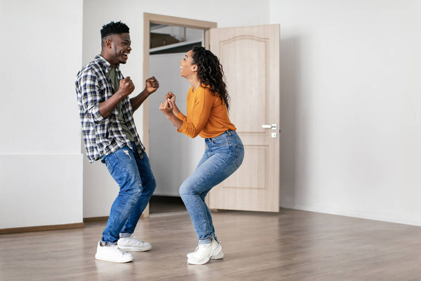 Joyful African American Couple Shaking Fists Celebrating Real Estate Purchase Moving To New House Posing Indoors. Housing For Young Family, Dreams Come True Concept - Foto, afbeelding