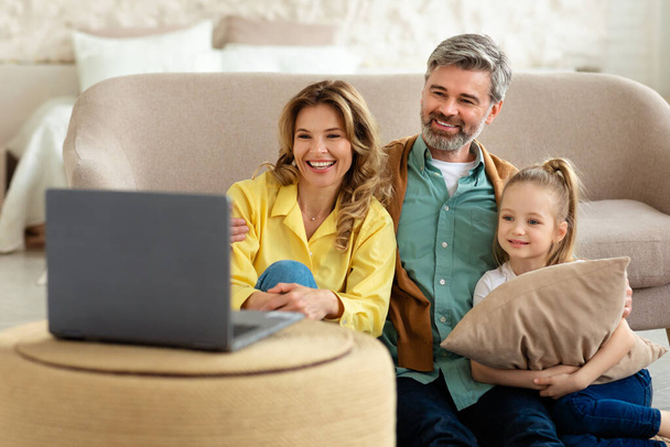 Cheerful Family Of Three Using Laptop Computer Watching Film Online Sitting Together At Home On Weekend. Internet Entertainment And Technology Lifestyle Concept - Foto, Imagem