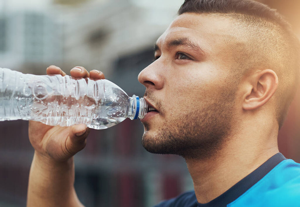 Give your body what it needs. a young man drinking from his water bottle while out for a run - Foto, immagini