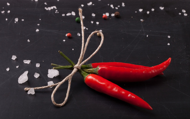 three related twine red hot peppers on a blackboard. With space  - Фото, изображение