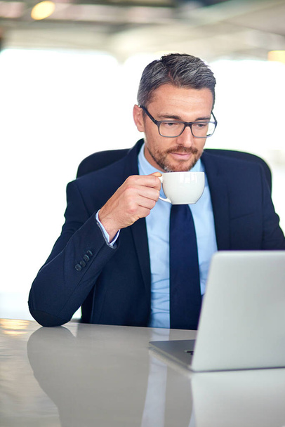 Читання і відповідь на його листи. бізнесмен п'є каву і використовує ноутбук в офісі
 - Фото, зображення