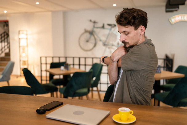 one man modern caucasian male wear shirt at cafe sit at the table taking a brake during work online remote having back or neck pain and strain stretching to relief tension business yoga copy space - Fotó, kép