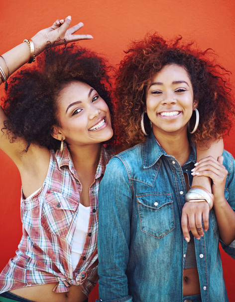 Best friends have double the fun. two young friends posing against a red background - 写真・画像