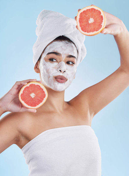 Skincare, health and face mask on a woman with a grapefruit doing an organic facial in studio. Girl with wellness, selfcare and healthy lifestyle doing a body care routine with tropical citrus fruit - Foto, afbeelding