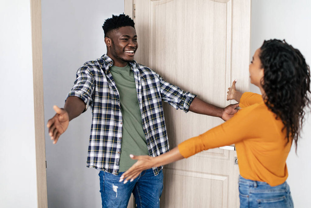 Cheerful Black Man And Lady Meeting Stretching Hands For An Embrace Standing Near Opened Entry Door At Home. Female And Male. Friendship Concept. Selective Focus - Fotoğraf, Görsel