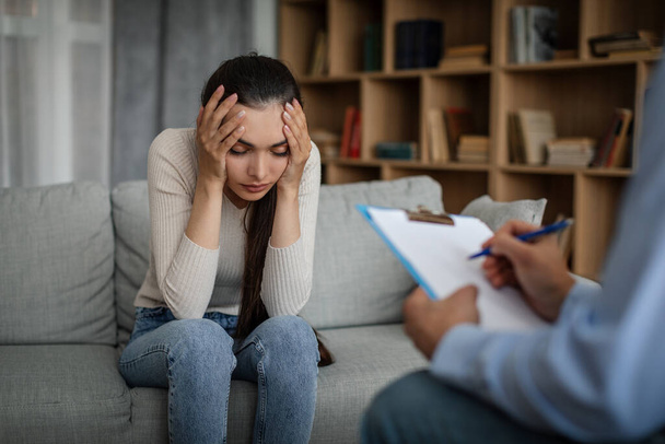 Despaired sad young caucasian lady suffering from mental problems listens to male doctor in office clinic interior. Prescription for depression treatment, medicine support, session with professional - Photo, Image
